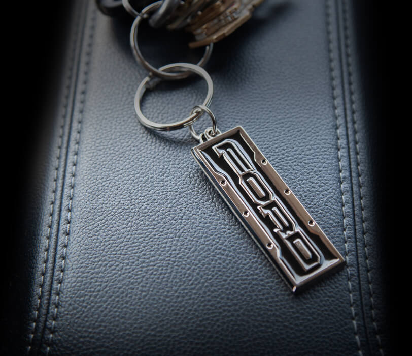 Metal Ford Keychain laying on a leather background