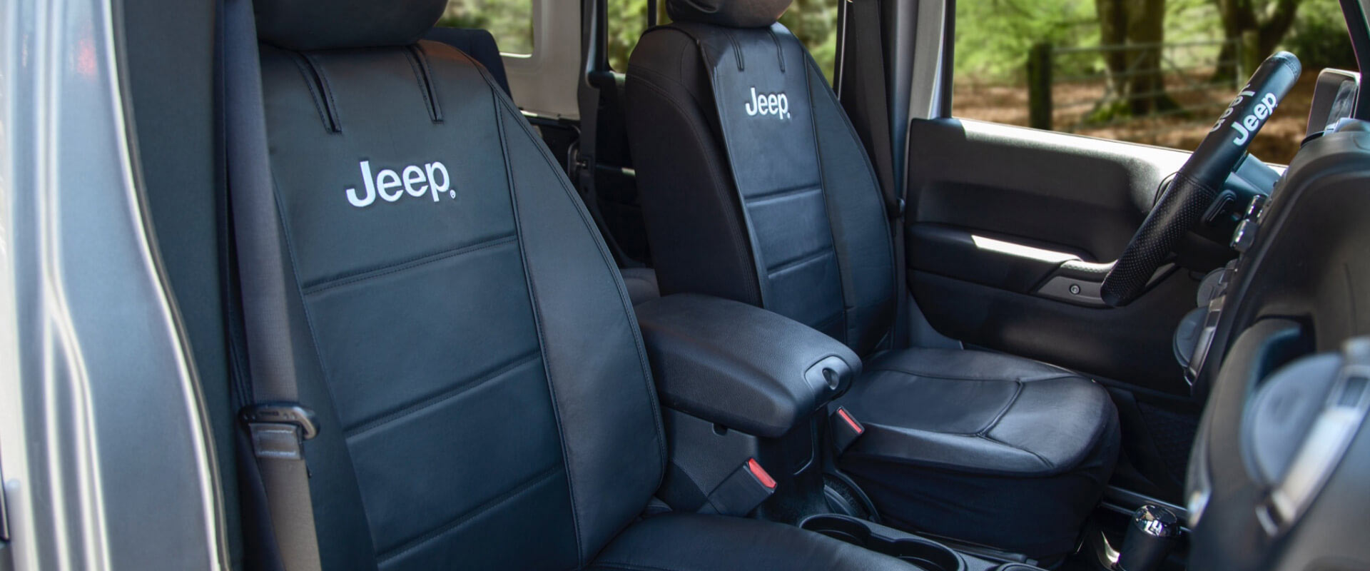 Black leather car seats with the "Jeep" logo are positioned inside a vehicle, suggesting a focus on automotive interior design.